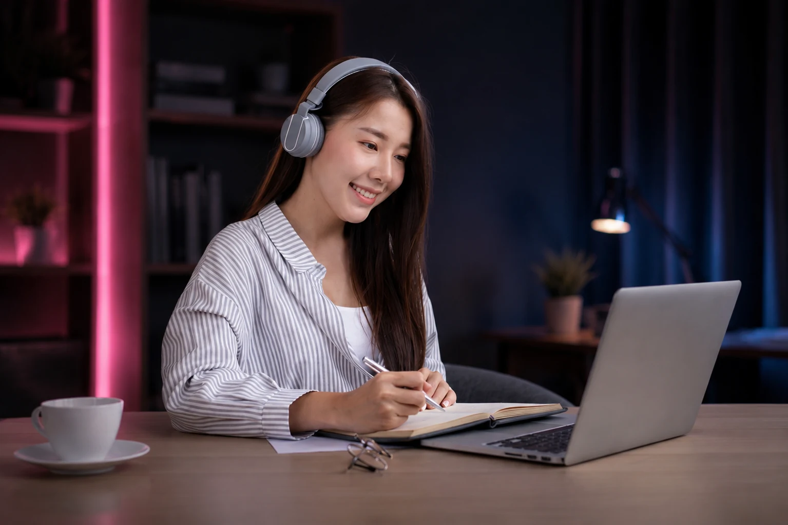ヘッドホンをつけて英語の音声を聞きながらノートに書いている女性